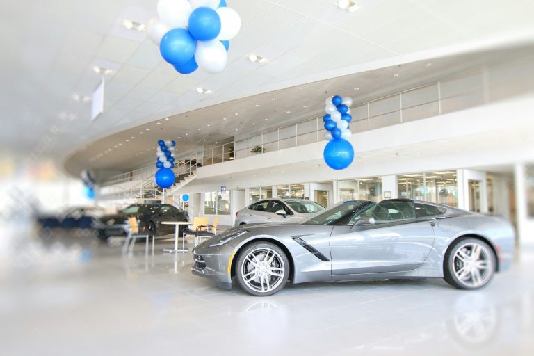 Silberner Sportwagen in modernem Ausstellungsraum mit blauen und weißen Ballons.